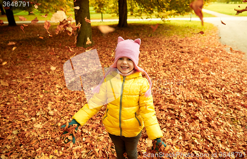 Image of happy girl playing with autumn leaves in park