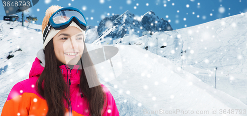 Image of happy young woman in ski goggles over mountains