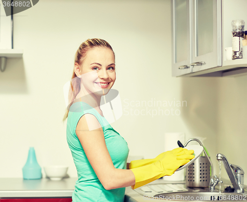 Image of happy woman washing dishes at home kitchen