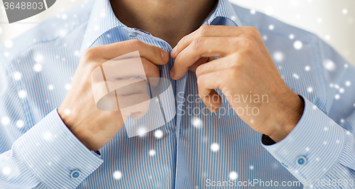 Image of close up of man fastening button on shirt