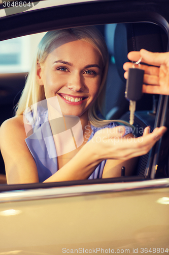 Image of happy woman getting car key in auto show or salon