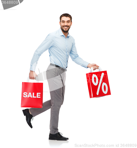 Image of smiling man walking with red shopping bag