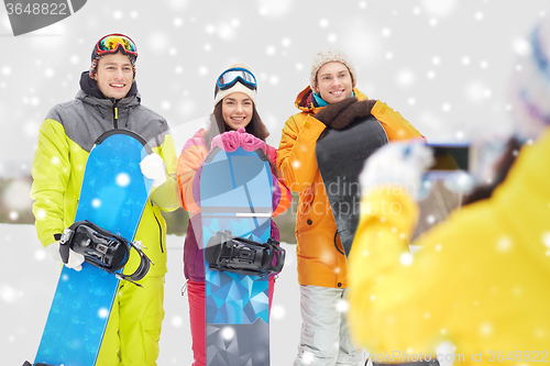 Image of happy friends with snowboards and smartphone