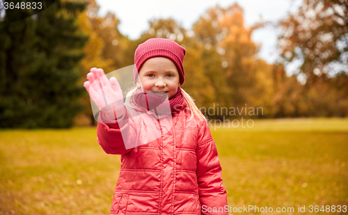 Image of happy little girl waving hand in autumn park
