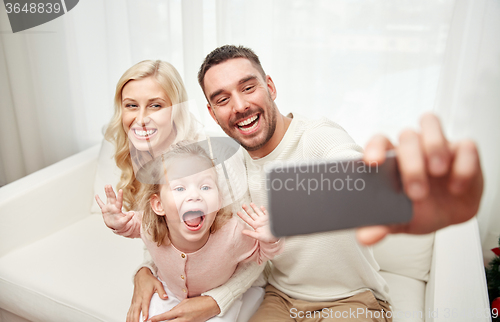 Image of family taking selfie with smartphone at home