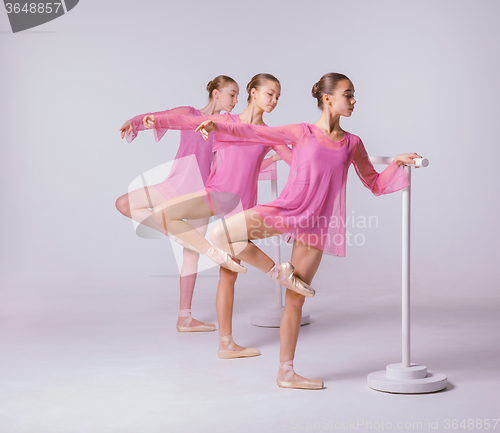 Image of Three young ballerinas stretching on the bar 