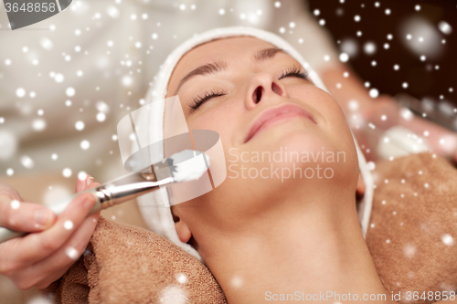 Image of woman face and beautician applying mask in spa