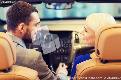 Image of happy couple sitting in car at auto show or salon