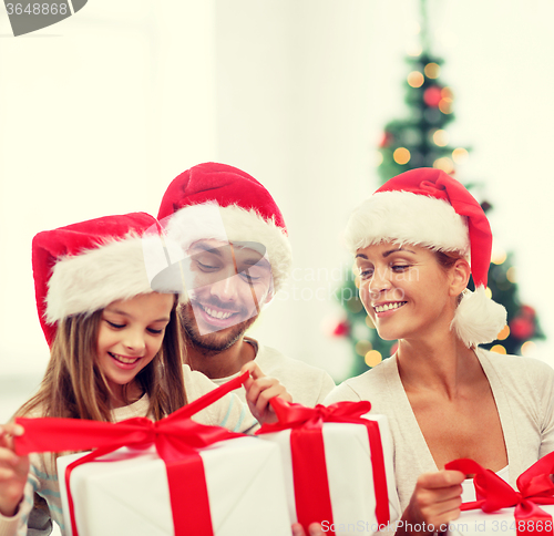 Image of happy family in santa helper hats with gift boxes