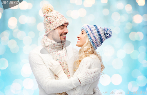 Image of happy couple in winter clothes hugging over lights