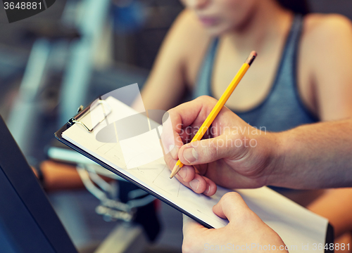 Image of close up of trainer hands with clipboard in gym