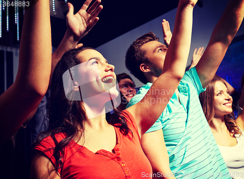 Image of smiling friends at concert in club