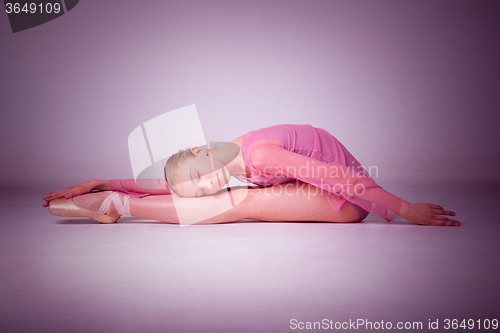 Image of The young ballerina posing on the floor 