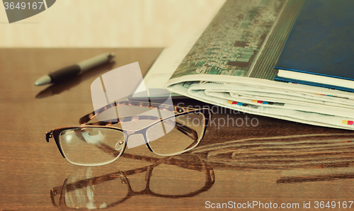 Image of Glasses and Newspapers on the table surface.