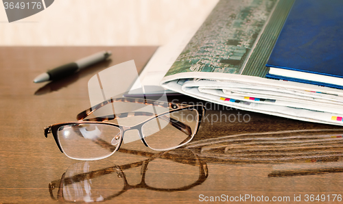 Image of Glasses and Newspapers on the table surface.