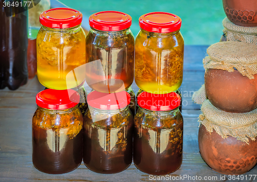 Image of Different varieties of honey in banks, offered for sale 