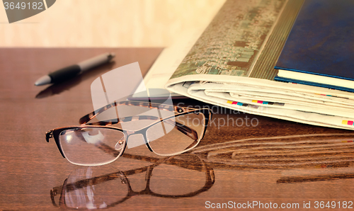 Image of Glasses and Newspapers on the table surface.