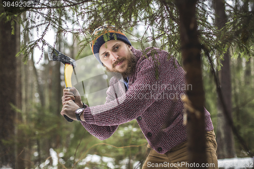 Image of Young man is cutting christmas tree in the wood