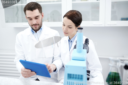 Image of scientists with tablet pc and microscope in lab