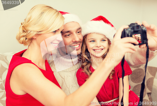 Image of smiling family in santa helper hats taking picture
