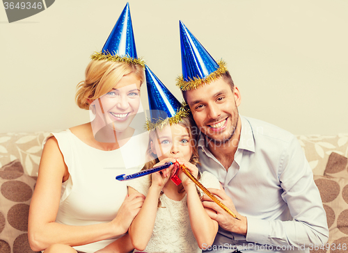 Image of smiling family in blue hats blowing favor horns