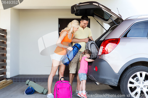 Image of happy family packing things to car at home parking