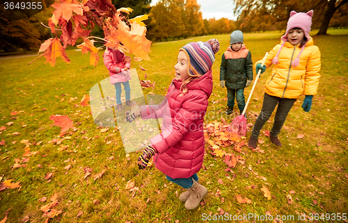 Image of happy children playing with autumn leaves in park