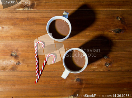 Image of christmas candy canes and cups on wooden table