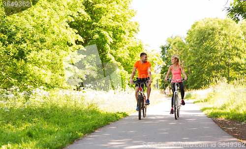 Image of happy couple riding bicycle outdoors