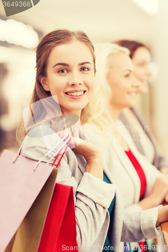 Image of happy young women with shopping bags in mall