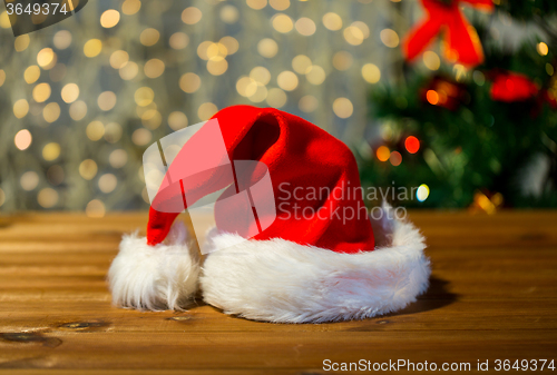 Image of close up of santa hat on wooden table over lights