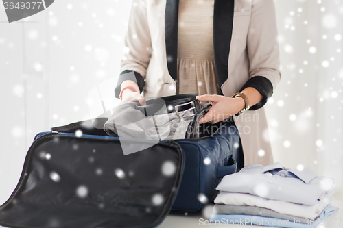 Image of woman packing formal male clothes into travel bag