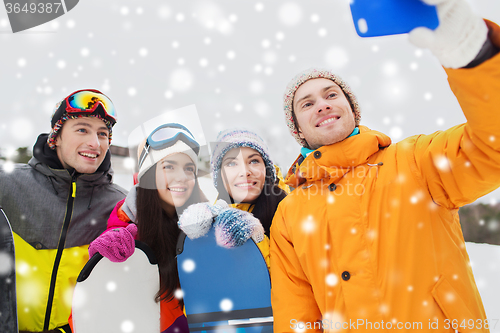 Image of happy friends with snowboards and smartphone