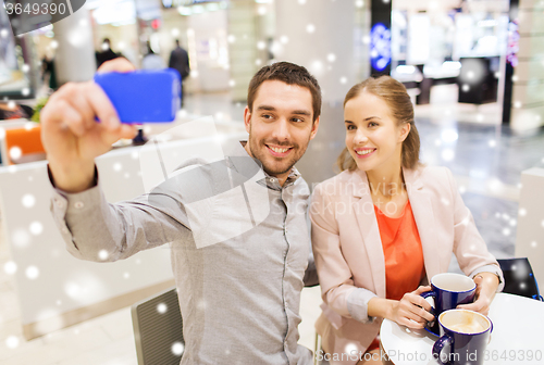 Image of happy couple with smartphone taking selfie in mall