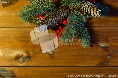 Image of close up of fir branch with cones on wooden table