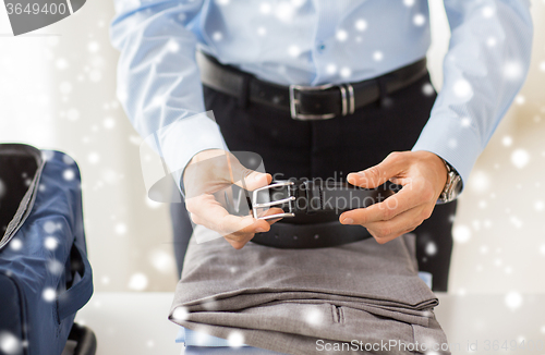 Image of businessman packing clothes into travel bag