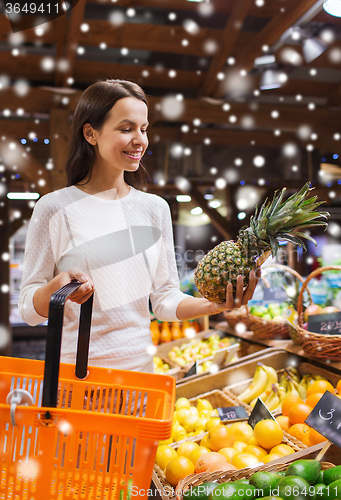 Image of happy young woman with food basket in market