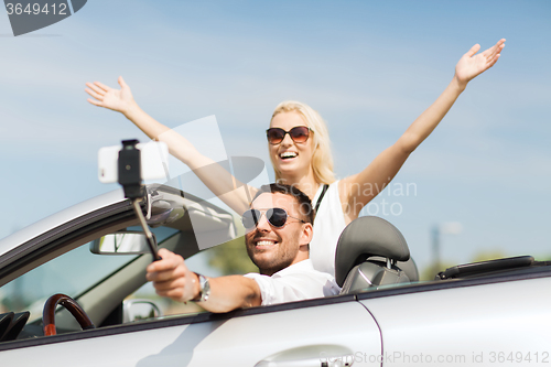 Image of happy couple in car taking selfie with smartphone