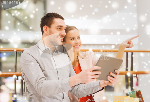 Image of couple with tablet pc and shopping bags in mall