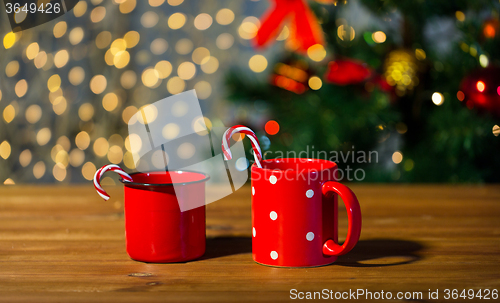 Image of christmas candy canes and cups on wooden table