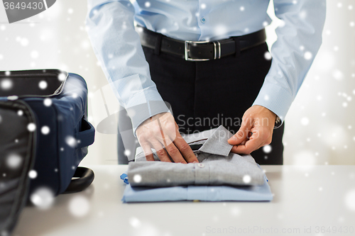 Image of businessman packing clothes into travel bag