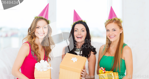 Image of three smiling women in pink hats with gift boxes