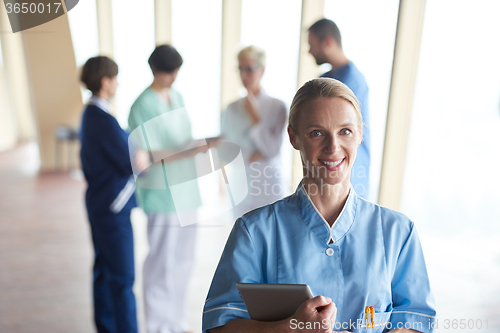 Image of female doctor with tablet computer  standing in front of team