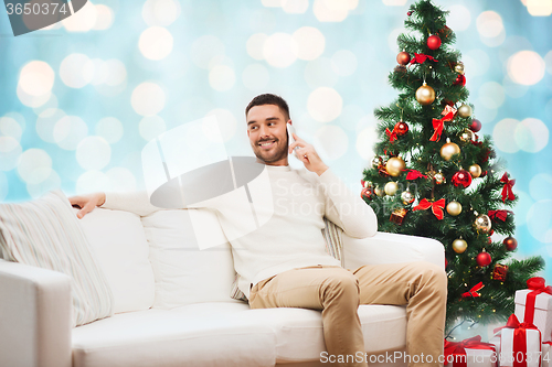 Image of man calling on smartphone over christmas lights