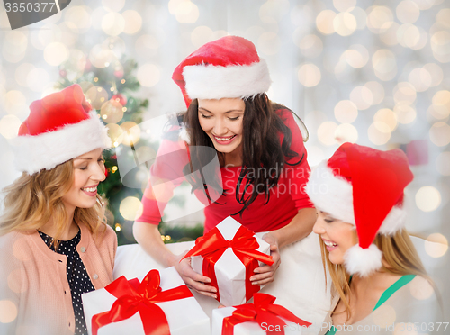 Image of happy women in santa hats with christmas gifts