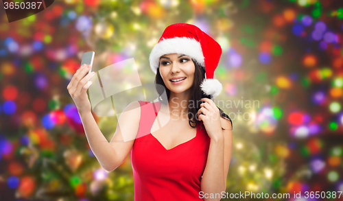 Image of woman in santa hat taking selfie by smartphone