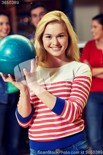 Image of happy young woman holding ball in bowling club