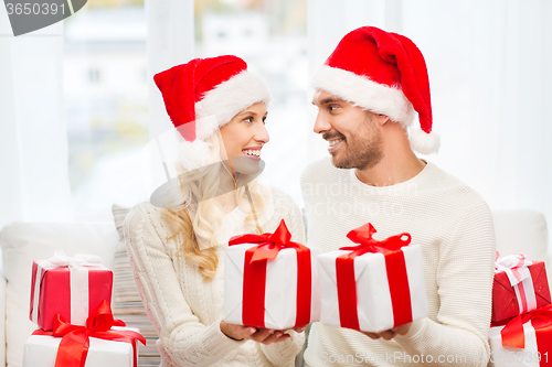 Image of happy couple at home exchanging christmas gifts