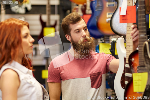 Image of couple of musicians with guitar at music store