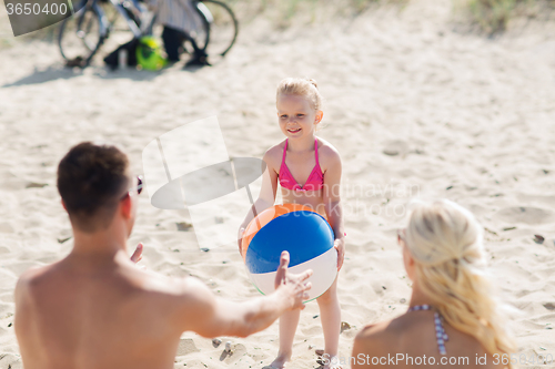 Image of happy family playing with inflatable ball on beach
